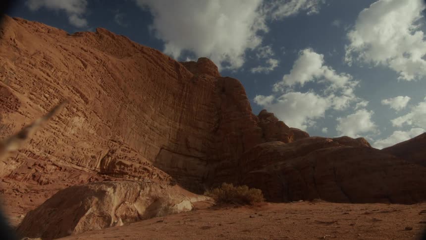 Time-lapse of clouds casting moving shadows across a majestic red rock canyon wall under a blue sky