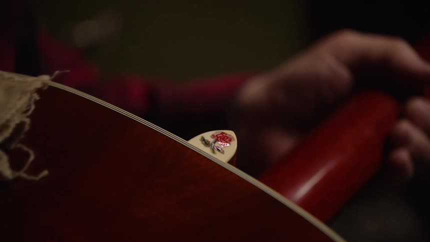 A musician gently cleans their cherished acoustic guitar with a soft cloth, revealing a decorative rose pick