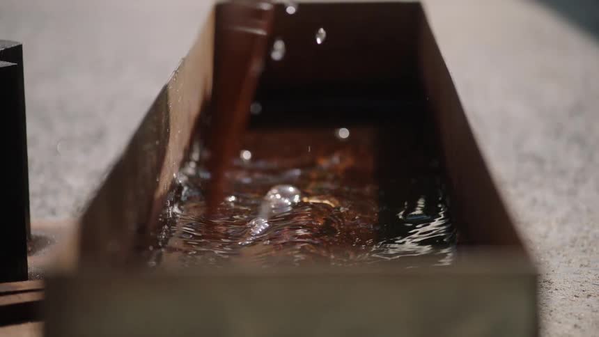 Close-up slow motion of a hand dipping and pulling out a piece of dark wood from a container of water