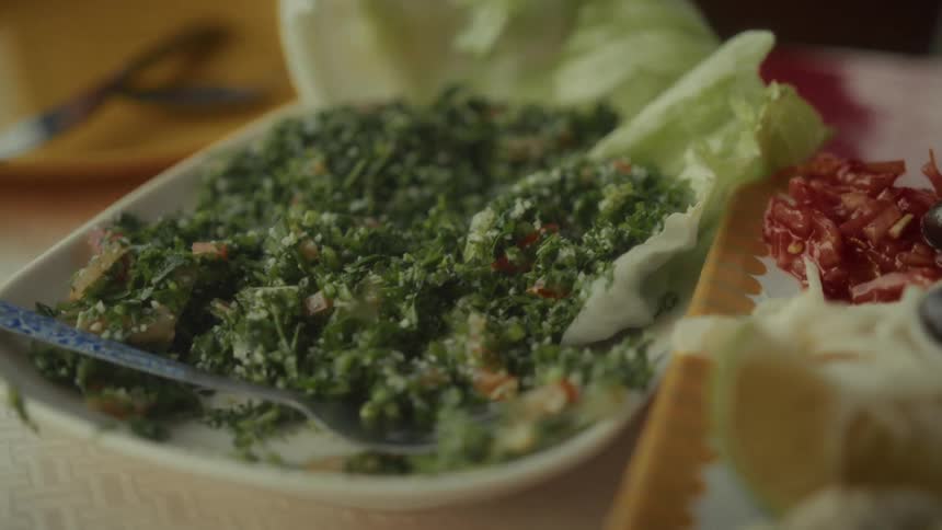 A close-up slow pull-back shot of a fresh tabbouleh salad served on a platter for a meal