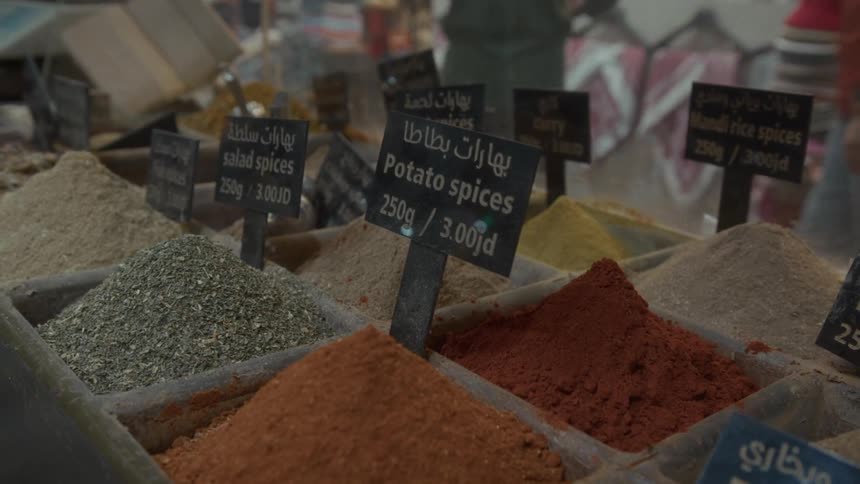 Vibrant mounds of ground spices with English and Arabic labels on display at a traditional Jordanian market