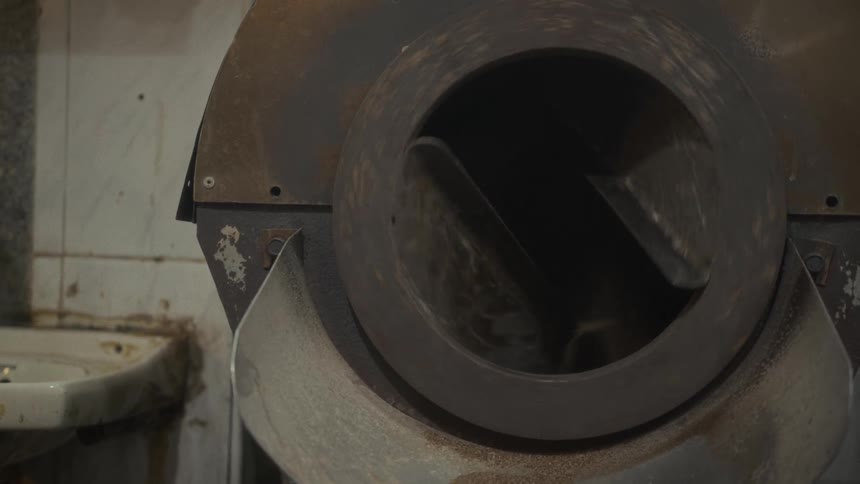Close-up of an industrial roasting machine with its rotating drum tumbling coffee beans during production