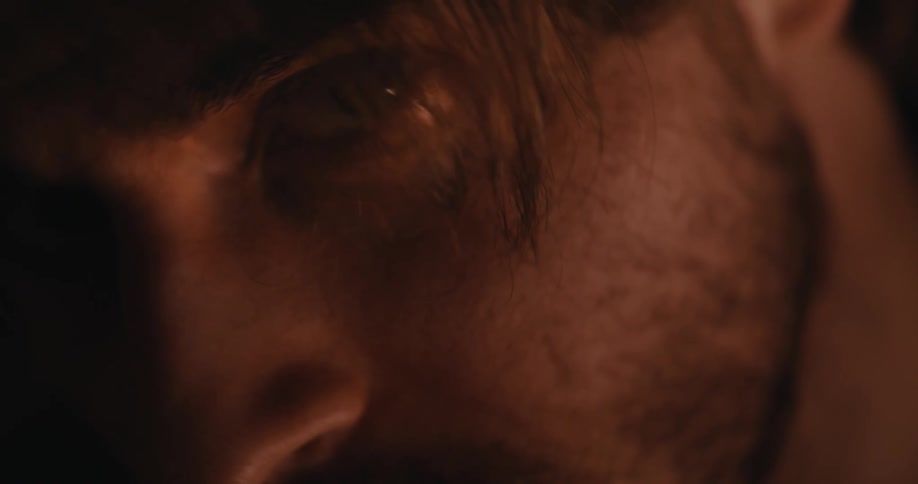 Intimate close-up of a man's focused eye illuminated by the warm, flickering glow of a fire