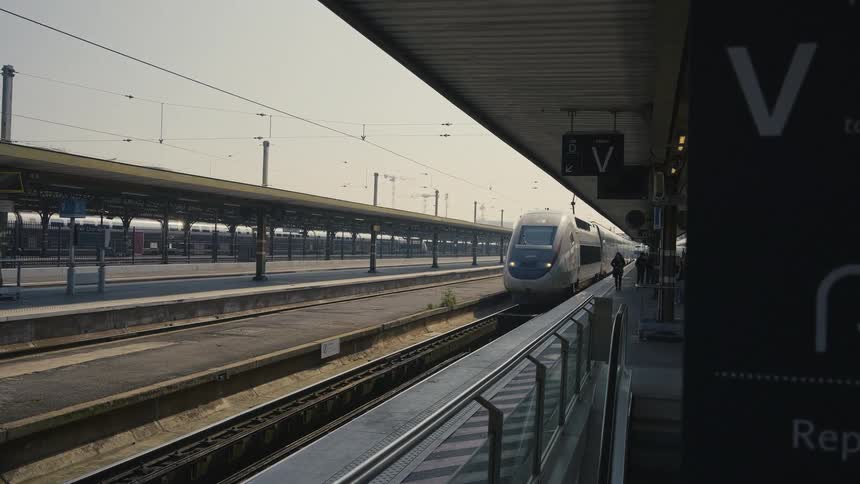 A French TGV high-speed train slowly arrives at the station platform on a sunny day