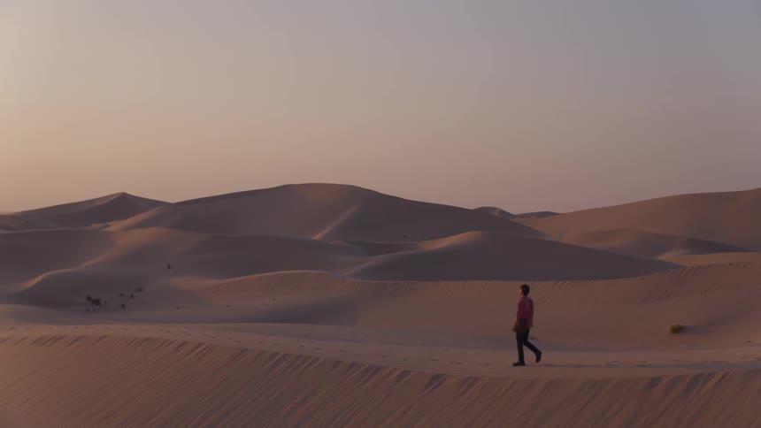 Person walks through the desert at sunset