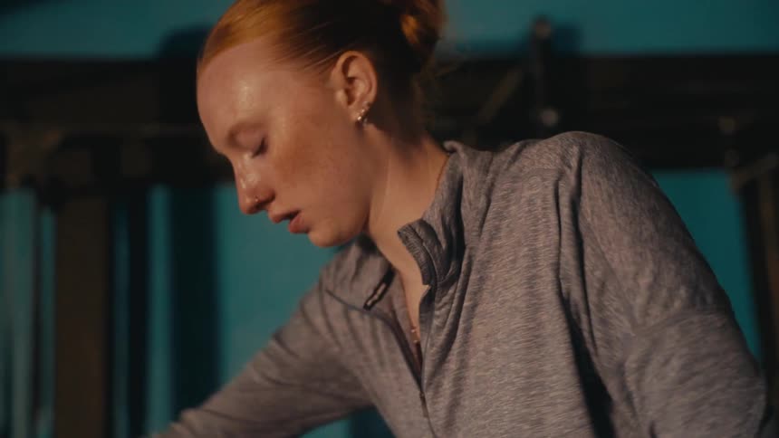 An intense close up of a focused redhead woman sweating during a workout