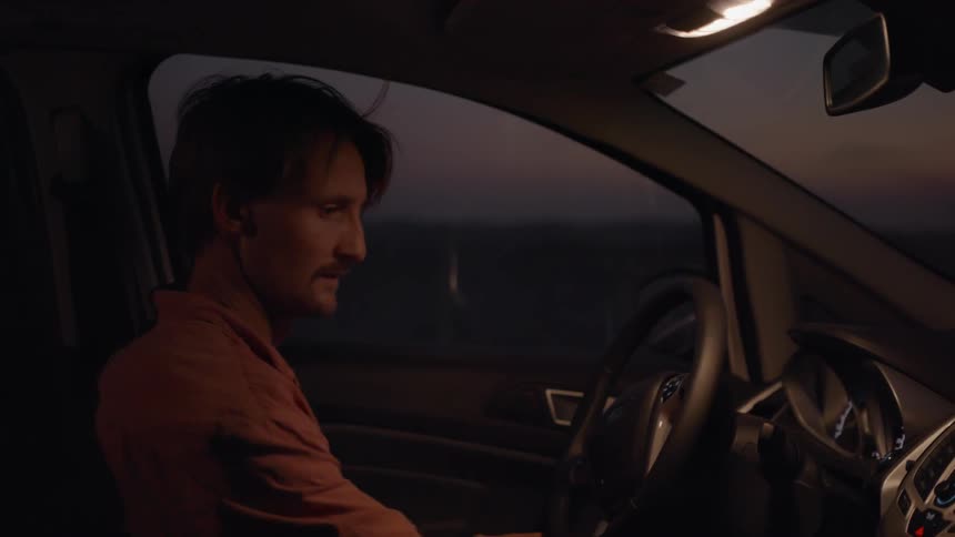 A man walks over and enters a car