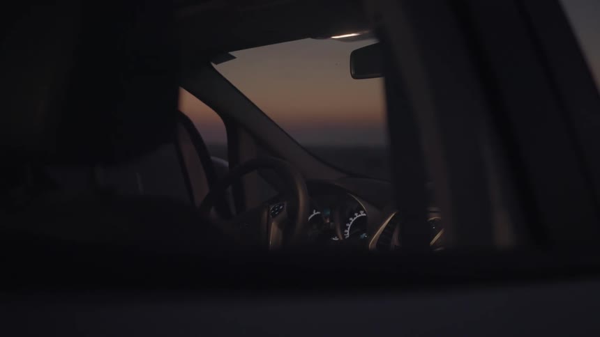 A person walks over to a car at dawn