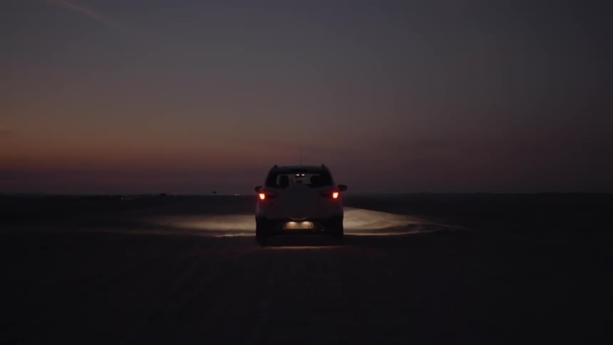 A car is driving in the sand at dawn