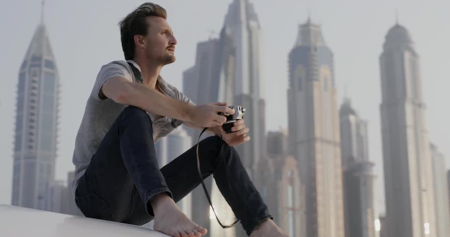 A man is sitting n a rooftop taking photographs
