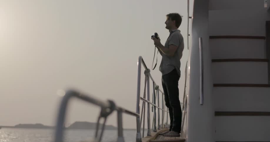 A man holds the railing as he walks on a boat