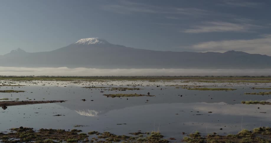 View of a body of water reflecting the mountains that are in the background under a cloudy sky