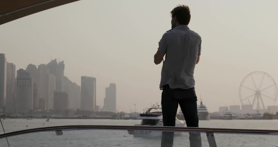 A man is taking photographs of a city from a boat