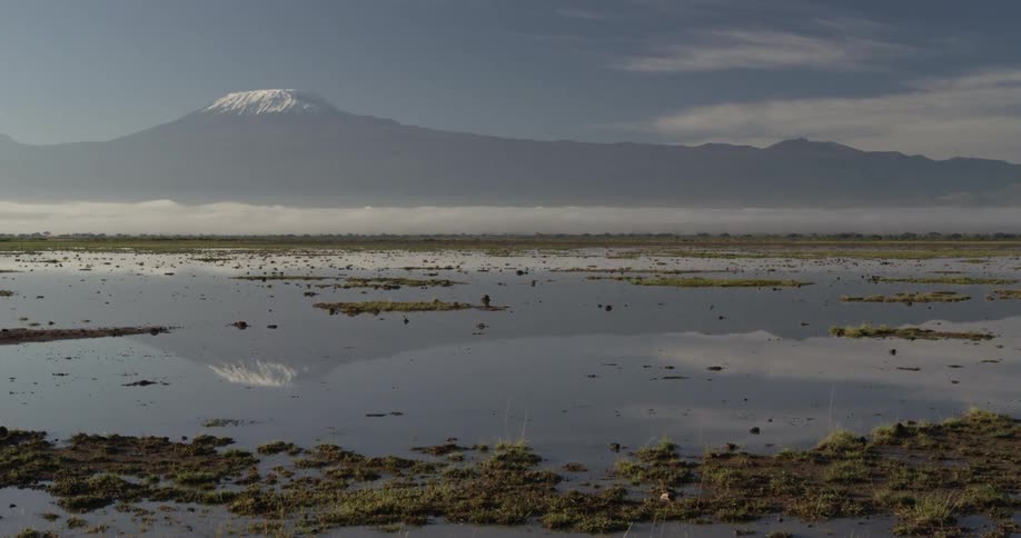 Snow capped mountains are seen across flat land