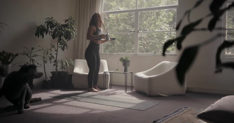 A woman walks over to a chair with a mug