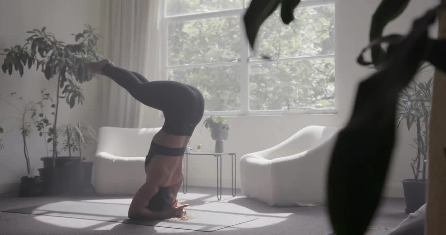 Woman practices yoga in the living room on a sunny day