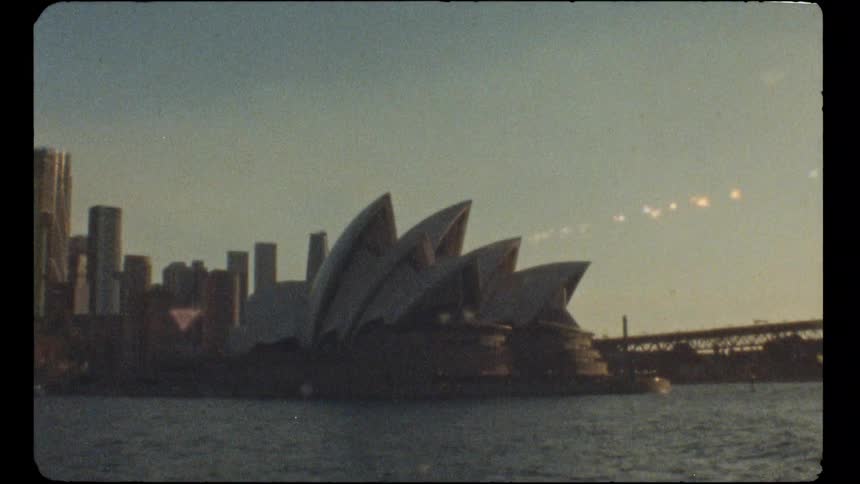 The iconic Sydney Opera House and city skyline captured on grainy, vintage 8mm film at dawn