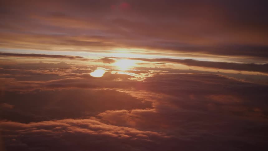 An awe-inspiring aerial view of a vibrant sunset casting a warm glow over a vast sea of clouds