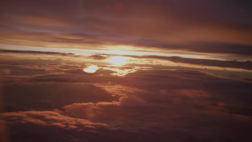 A serene aerial view of a golden sunset from above a vast and beautiful sea of clouds