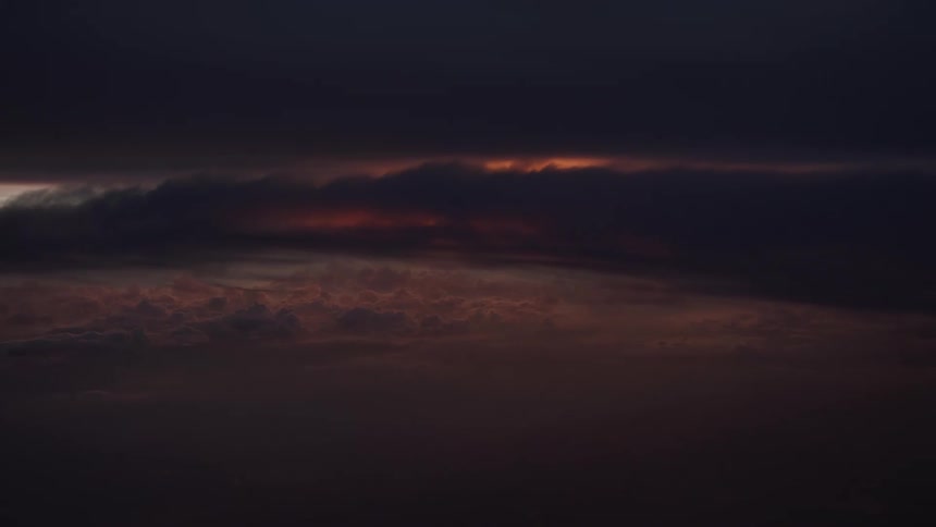 A dramatic and dark sky shows the last sliver of a sunset glowing behind heavy clouds