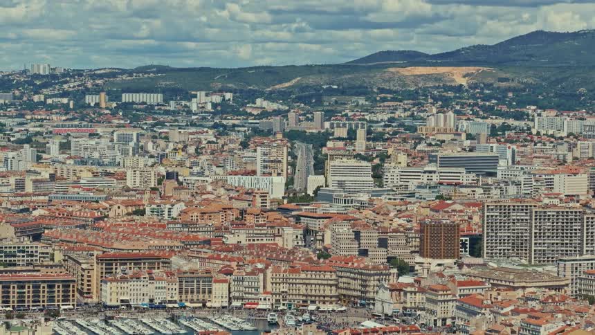 High-angle panoramic view of the historic city of Marseille, France, with traffic flowing through the streets on a cloudy day