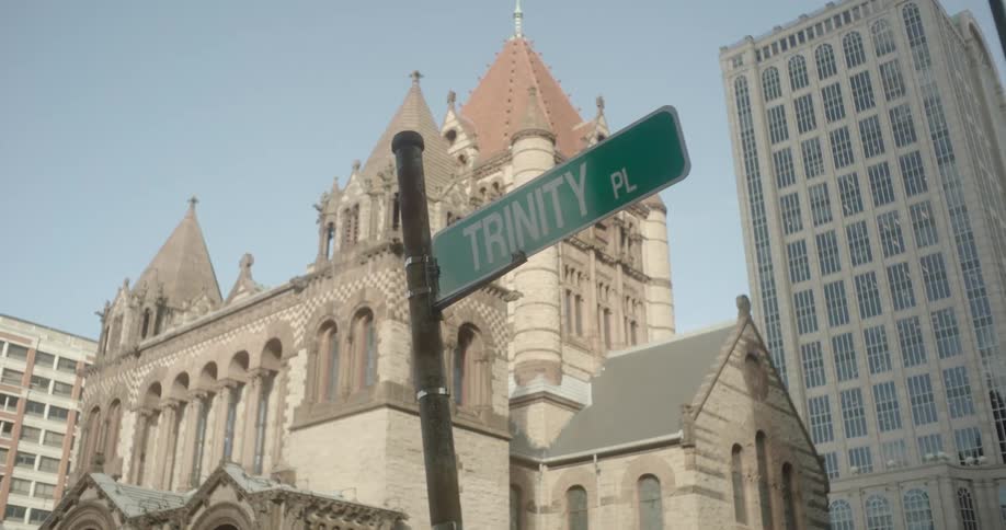 A slow-motion dolly shot reveals the historic Trinity Church in Boston with a street sign in the foreground