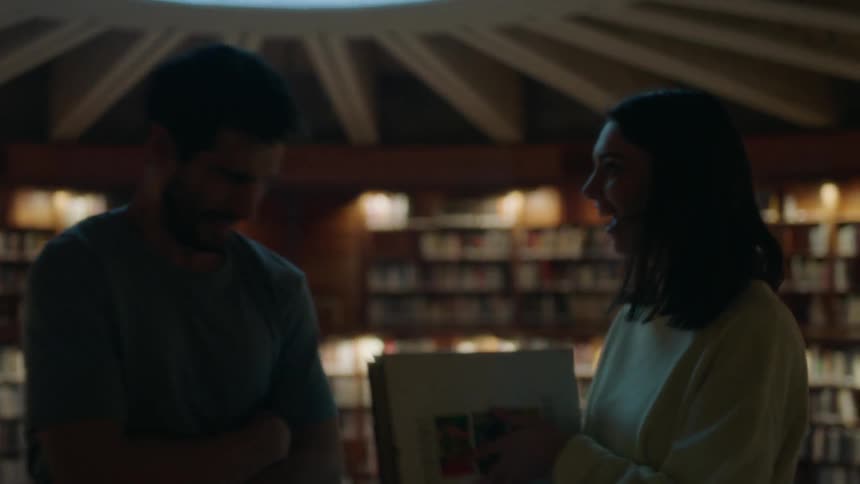Woman snapping a book closed playfully in a man's face while in a bookstore