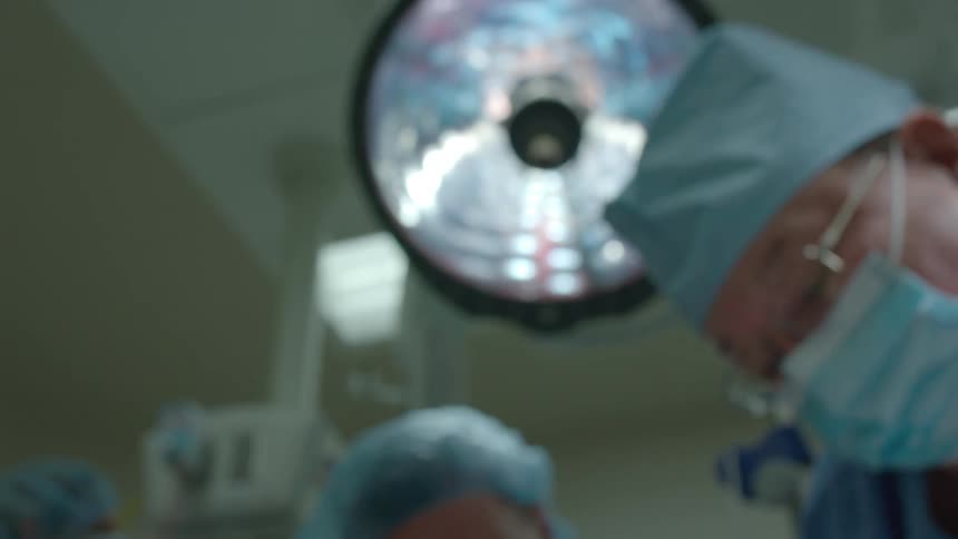A soft focus, patient's point of view shot looking up at a team of surgeons in the operating room