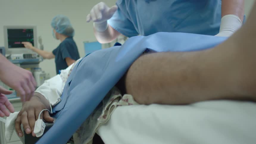 From a patient's point-of-view, a surgeon stands over them on an operating table as a nurse monitors their vitals