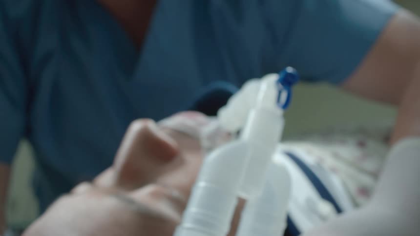 A team of medical professionals work on an unconscious patient connected to a ventilator in a hospital