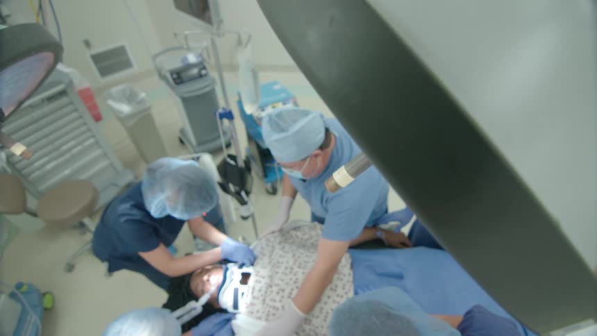 High-angle view of a team of dentists and assistants performing oral surgery on a patient in a modern operating room
