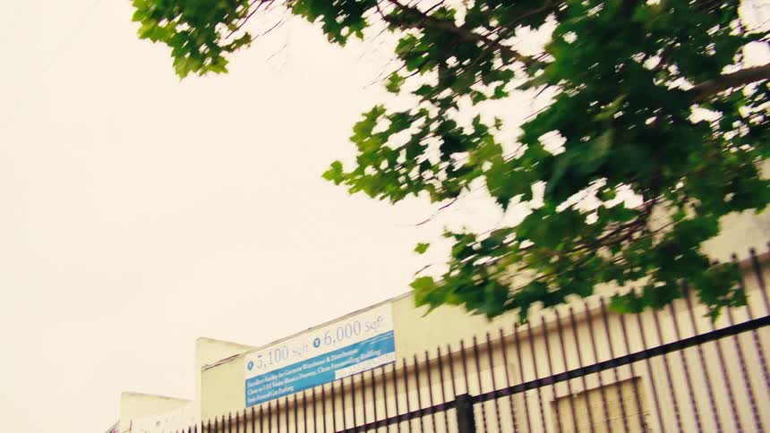 A low-angle point-of-view shot driving past colorful storefronts and industrial buildings in an urban area