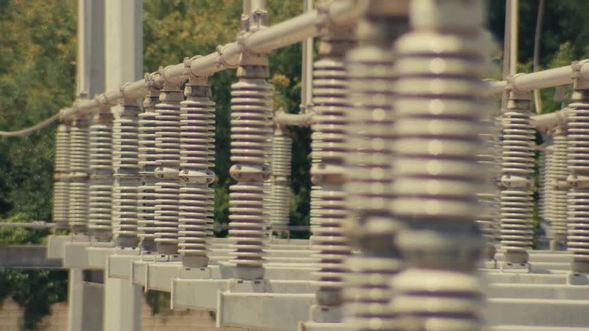 Close-up rack focus shot of high-voltage insulators at an electrical power substation