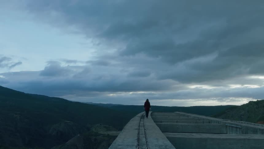 A woman walks along a cement wall