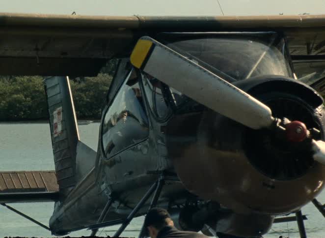 Close-up panning shot of a vintage propeller seaplane docked on a calm body of water