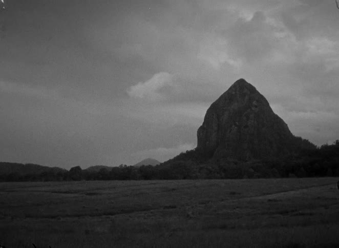 Dramatic black and white film captures lightning flashing over a silhouetted mountain during a powerful nighttime thunderstorm