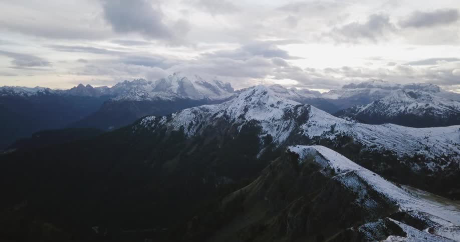 Clouds hover over snow-capped peaks in a mountain range