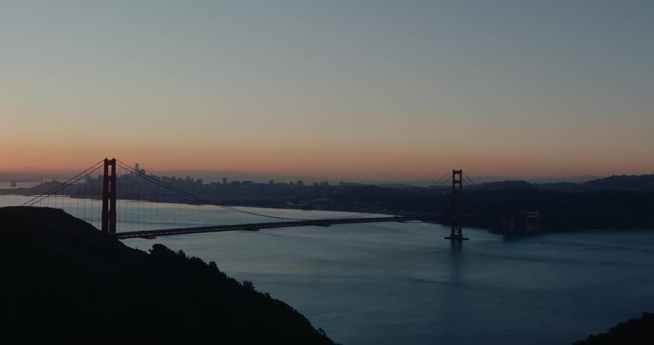 A serene wide shot of the iconic Golden Gate Bridge and the San Francisco skyline at dawn from the Marin Headlands