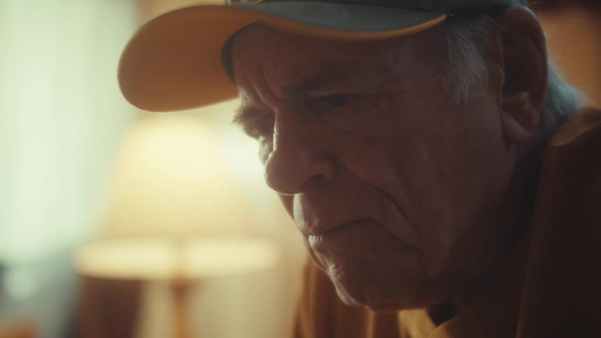 A close-up of a somber elderly veteran's face as he sits in quiet contemplation