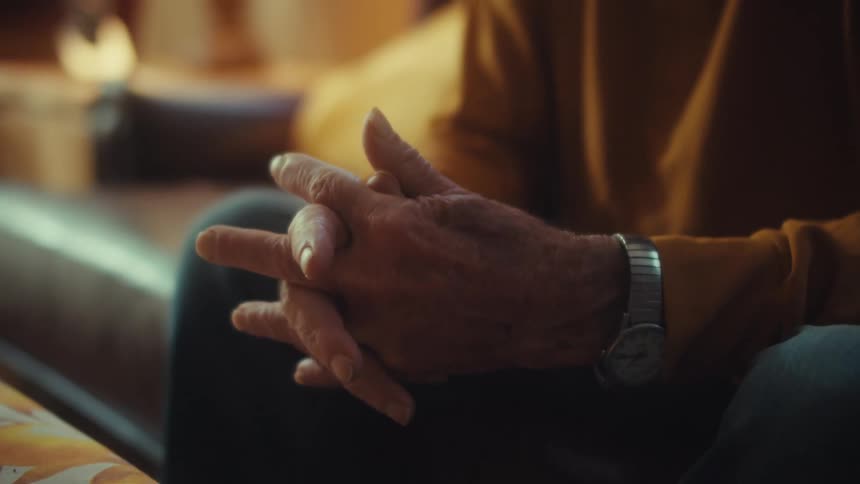 Slow focus pull from a tablet to the somber face of an elderly US Army veteran watching the screen