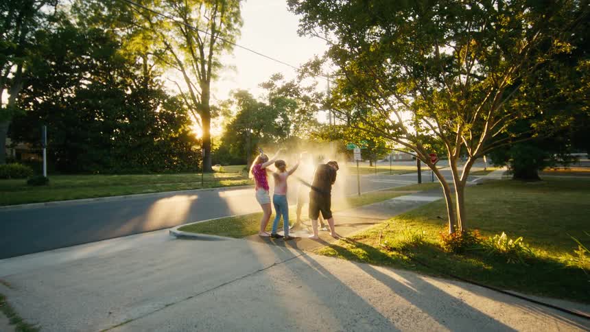 A group of young friends celebrate with a confetti popper on the sidewalk during a beautiful summer sunset