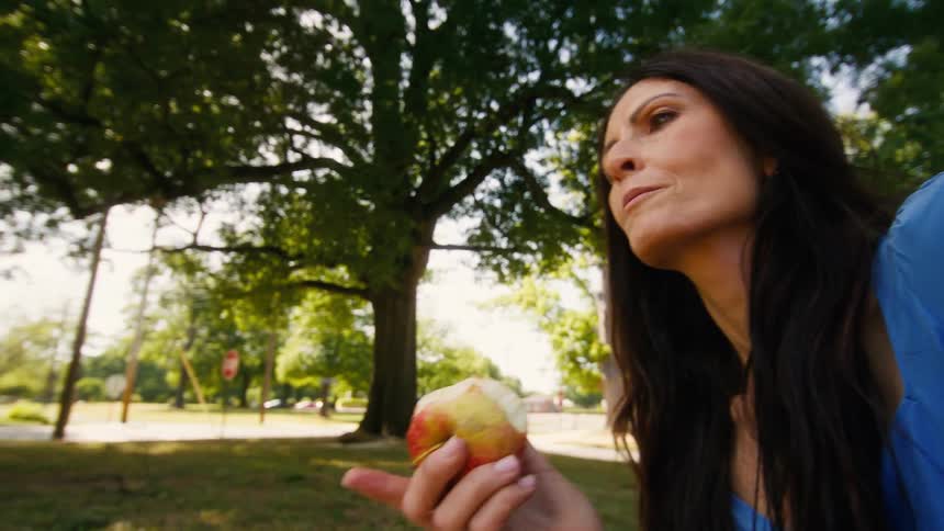 Close up of a mother and her son enjoying a healthy apple snack in a park on a sunny day