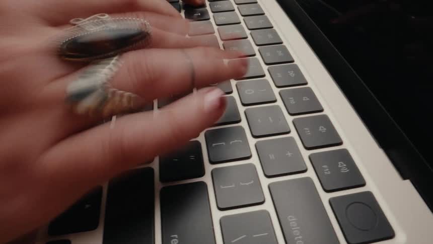 A close-up, time-lapse shot captures the motion blur of fingers rapidly typing on a laptop keyboard