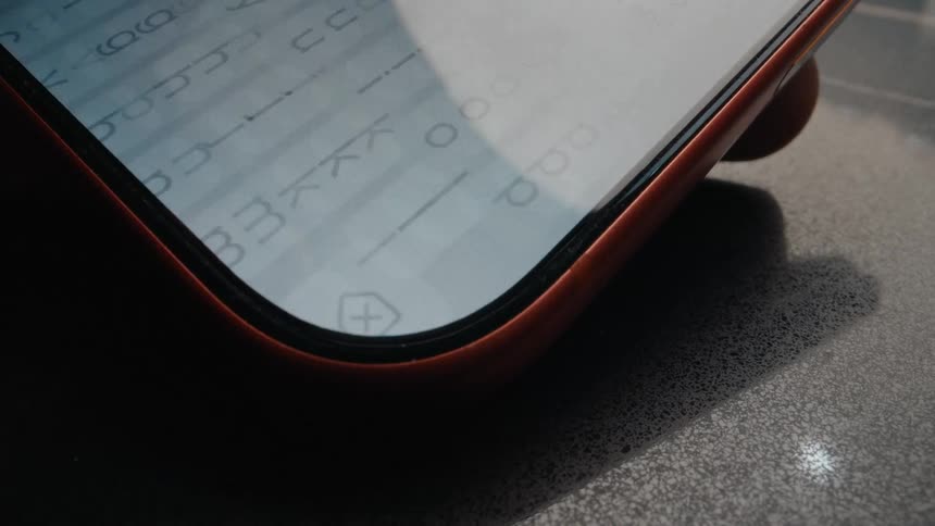 A macro view of a finger tapping an icon on a smartphone screen, revealing the digital keyboard