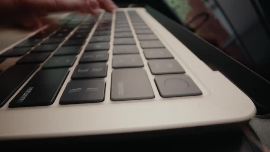 A dynamic time-lapse captures a close-up of fingers rapidly typing across a laptop keyboard