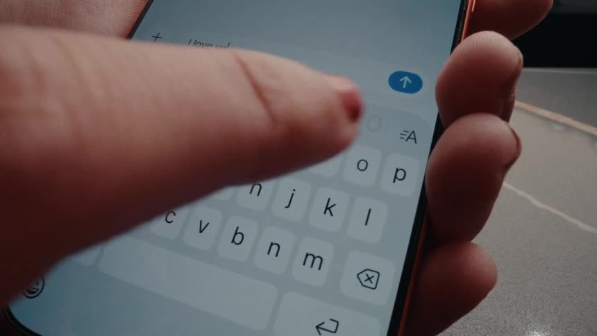 A close-up shot of a person sending an 'I love you' text message on a smartphone