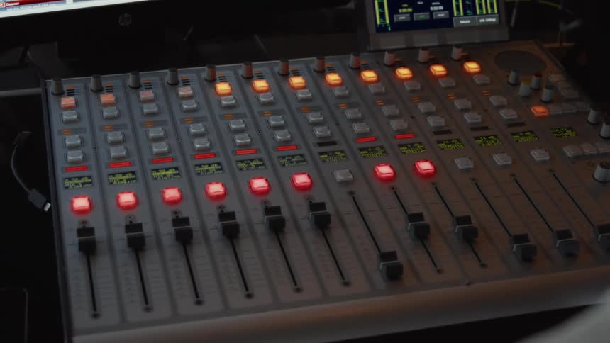 Close-up of a professional audio mixing console with glowing buttons in a recording studio