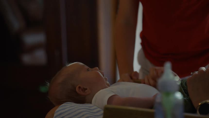A big brother affectionately leans over his newborn sibling, giving them a gentle kiss on the nose