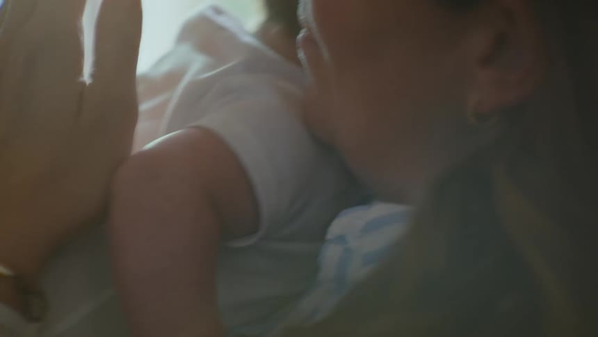 A loving mother holds her newborn baby close, gently patting their back in a tender embrace