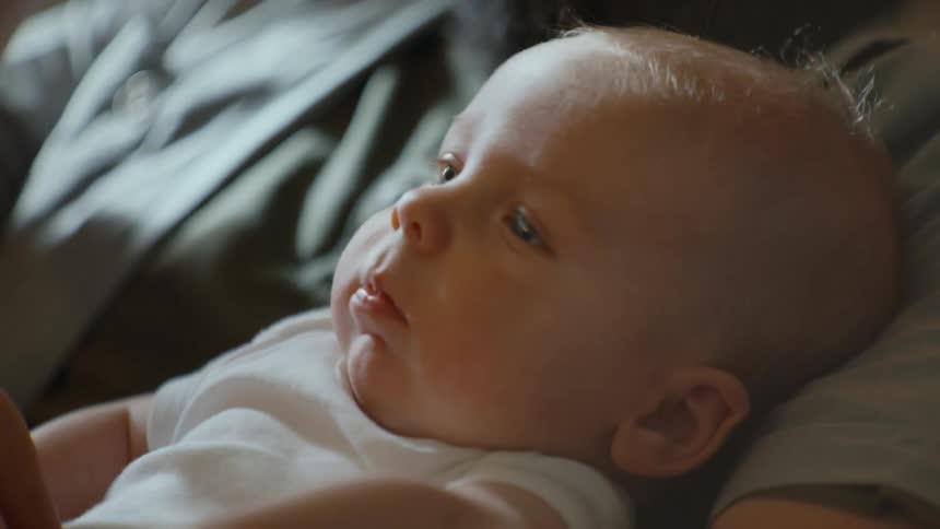 A gentle bearded father lovingly holds his newborn baby in a quiet, tender moment